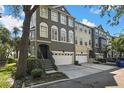 A charming three-story townhome featuring a two-car garage, a cozy entryway staircase, and a well-maintained front yard at 1402 Harbour Walk Rd, Tampa, FL 33602