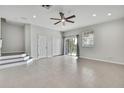 A large empty living room with tiled floors, a ceiling fan, neutral paint, and sliding glass doors for ample natural light at 1402 Harbour Walk Rd, Tampa, FL 33602