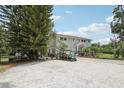 Spacious home with a large gravel driveway, lush landscaping, and ample parking for multiple vehicles at 1709 Main St, Safety Harbor, FL 34695