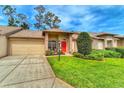 Charming single-story home featuring manicured landscaping, a two-car garage, and a welcoming red front door at 18531 Bent Pine Dr, Hudson, FL 34667