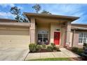 Inviting front porch featuring a bright red door with a wreath, seating, and manicured landscaping at 18531 Bent Pine Dr, Hudson, FL 34667