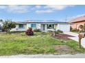 The front of this well-kept home features a manicured lawn, solar panels, and an attached garage at 18702 Van Nuys Cir, Port Charlotte, FL 33948