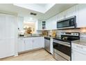 Bright kitchen featuring stainless steel appliances, granite countertops, and white cabinets at 2238 Lark W Cir # D, Palm Harbor, FL 34684