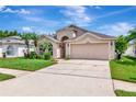 Charming home featuring a two-car garage and beautifully landscaped front yard with palm trees, perfect for curb appeal at 30445 Tremont Dr, Wesley Chapel, FL 33543