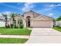 Charming home featuring a two-car garage and beautifully landscaped front yard with palm trees, enhancing its curb appeal at 30445 Tremont Dr, Wesley Chapel, FL 33543