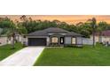 Inviting single-story home with a neatly landscaped yard, freshly painted driveway, and attached garage at 4264 Michaler St, North Port, FL 34286