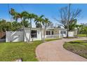 Landscaped yard with mature palm trees and a circular driveway of a charming single-story home at 709 Pruitt Dr, Madeira Beach, FL 33708