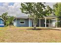 Charming blue home featuring a carport, complemented by a mature shade tree at 7307 34Th N Ave, St Petersburg, FL 33710