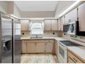 Well-lit kitchen with neutral cabinets, stainless steel refrigerator, and a double sink under a window at 7712 40Th N Ter, St Petersburg, FL 33709