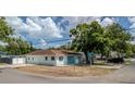 A cozy light blue house features a well-maintained lawn, a brown roof, and a secure chain-link fence at 8525 N Ola Ave, Tampa, FL 33604