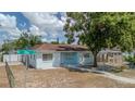 Charming single-story home featuring a light blue exterior, a cozy front yard, and a concrete walkway leading to the front door at 8525 N Ola Ave, Tampa, FL 33604