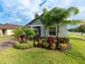 Charming home with well-manicured lawn, paver drive, and tropical landscaping featuring multiple palm trees at 11714 Sunburst Marble Rd, Riverview, FL 33579
