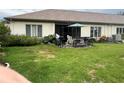 Spacious backyard featuring a patio set with a grill, chairs, and an umbrella, surrounded by a lush lawn at 18804 Tournament Trl, Tampa, FL 33647