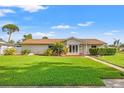 Charming single-story home featuring a well-manicured lawn, mature landscaping, and inviting walkway to the front door at 2006 Tanglewood Ne Dr, St Petersburg, FL 33702