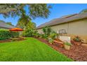The backyard features beautiful landscaping, mulch and an orange umbrella over outdoor seating at 3000 Naughton Way, Tarpon Springs, FL 34688