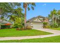 Beautiful landscaped yard with tropical plants surrounding the home and a two-car garage at 3000 Naughton Way, Tarpon Springs, FL 34688
