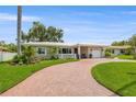 Charming single-story home with a curved red brick driveway and well-manicured lawn and tropical landscaping at 715 45Th Ne Ave, St Petersburg, FL 33703