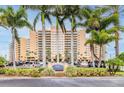Exterior of the luxury residence featuring a manicured lawn and towering palm trees framing the building's sign at 880 Mandalay Ave # C1103, Clearwater Beach, FL 33767