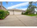 Charming single-story home featuring a three-car garage, well-manicured lawn, and lush tropical landscaping at 9402 Woodbay Dr, Tampa, FL 33626