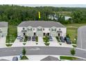 Aerial view showcases townhomes with driveways, landscaping, and a serene lake in the background at 11054 Crescent Deer Dr, Land O Lakes, FL 34638
