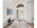 Chic entryway featuring light tile floors, a modern bench, and a striking arched glass double door at 1741 Beaconsfield Dr, Wesley Chapel, FL 33543