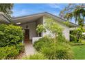 Well-maintained home exterior features an established landscape with a mature shade tree and partial front porch view at 2035 Nolan Dr, Dunedin, FL 34698