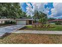 Inviting single-story home featuring a two-car garage, stone accents, and tropical landscaping at 2063 Ridgecrest Dr, Dunedin, FL 34698