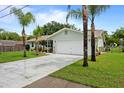 Well-maintained home with a two-car garage, lush lawn, and mature landscaping including palm trees at 39243 6Th Ave, Zephyrhills, FL 33542