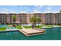 Condo building featuring a tennis court, pool, and boat dock on a sunny day at 5445 Gulf Blvd # 210, St Pete Beach, FL 33706