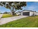 Charming single-story home with a well-manicured lawn, a dark garage door, and mature trees at 6920 13Th N Ave, St Petersburg, FL 33710