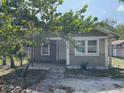 Single-story home exterior with neutral paint and simple landscaping, partially shaded by a mature tree at 7806 N Orleans Ave, Tampa, FL 33604