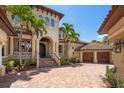 Stately two-story home showcasing arched windows, a brick driveway, and lush tropical landscaping at 841 Ponce De Leon Dr, St Petersburg, FL 33715