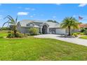 Expansive single-story home with a paved driveway, lush lawn, and beautifully landscaped yard at 9276 Ashley Dr, Weeki Wachee, FL 34613