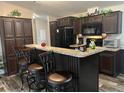 Cozy kitchen features dark cabinetry, breakfast bar with seating, and black appliances at 12426 Terra Ceia Ave, New Port Richey, FL 34654