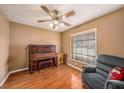 Comfortable bedroom with a ceiling fan, hardwood floors, and a cozy recliner near the window at 15820 Sapwood St, Tampa, FL 33624