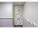 Elegant white entry door with classic gold hardware and decorative panels in a neutral hallway setting at 1651 Sand Key Estates Ct # 54, Clearwater Beach, FL 33767