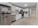 Modern kitchen featuring stainless steel appliances, white cabinets, and light wood flooring at 4218 E Cayuga St, Tampa, FL 33610