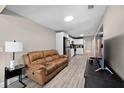 View of living room with a brown leather sofa and hardwood floors that flows into kitchen space at 4218 E Cayuga St, Tampa, FL 33610
