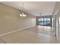 Spacious living room featuring tile floors, ceiling fan, chandelier, and sliding doors offering a waterfront view at 530 S Gulfview Blvd # 203, Clearwater Beach, FL 33767