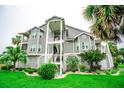 Exterior angle view of a condo building with balconies, white stairs and tropical landscaping at 5712 Biscayne Ct # 201, New Port Richey, FL 34652