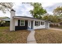 This beautiful home boasts a striking black-and-white exterior, a chimney, and a well-maintained front lawn at 5801 N 17Th St, Tampa, FL 33610