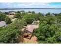 Aerial view of a cozy home surrounded by lush trees and showcasing a wooden deck at 611 Shore E Dr, Oldsmar, FL 34677