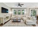 Bright living room with an oversized sectional couch, large windows, and stylish decor on hardwood floors at 6214 Windship Ct, Tampa, FL 33647