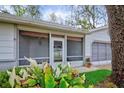 Close-up of the front entry with screened-in porch and well-maintained landscaping at 8619 Gold Pine Dr, Port Richey, FL 34668