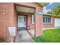 Inviting brick porch with 'Welcome' decor, plants, and views of the front yard at 13296 88Th N Ave, Seminole, FL 33776