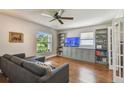 Cozy living room features hardwood floors, a gray sectional, custom built-ins, and a large window at 150 Bosphorous Ave, Tampa, FL 33606
