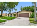 Charming one-story home featuring a brown two-car garage, well-maintained lawn, and inviting front porch area at 2329 Carrie Ct, Dunedin, FL 34698