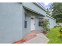 Exterior view of front entrance featuring a white door, brick walkway, and a small garden at 26343 Whirlaway Ter, Wesley Chapel, FL 33544