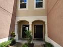 Townhome front entrance featuring a covered porch, columns, and a dark-colored front door at 26541 Chimney Spire Ln, Wesley Chapel, FL 33544