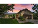 Charming single-story home featuring a well-manicured lawn, a two-car garage, and lovely landscaping at dusk at 3115 Westridge Dr, Holiday, FL 34691